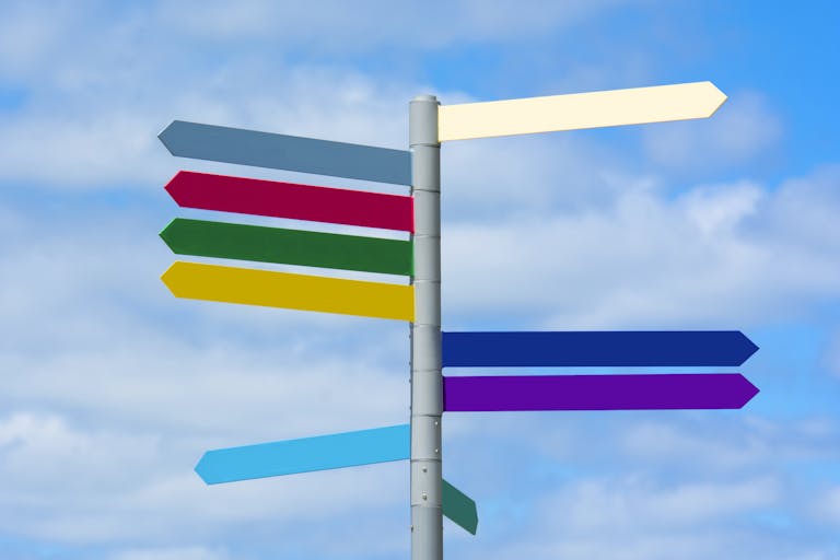 Multicolored directional signpost against a vibrant blue sky, offering guidance.